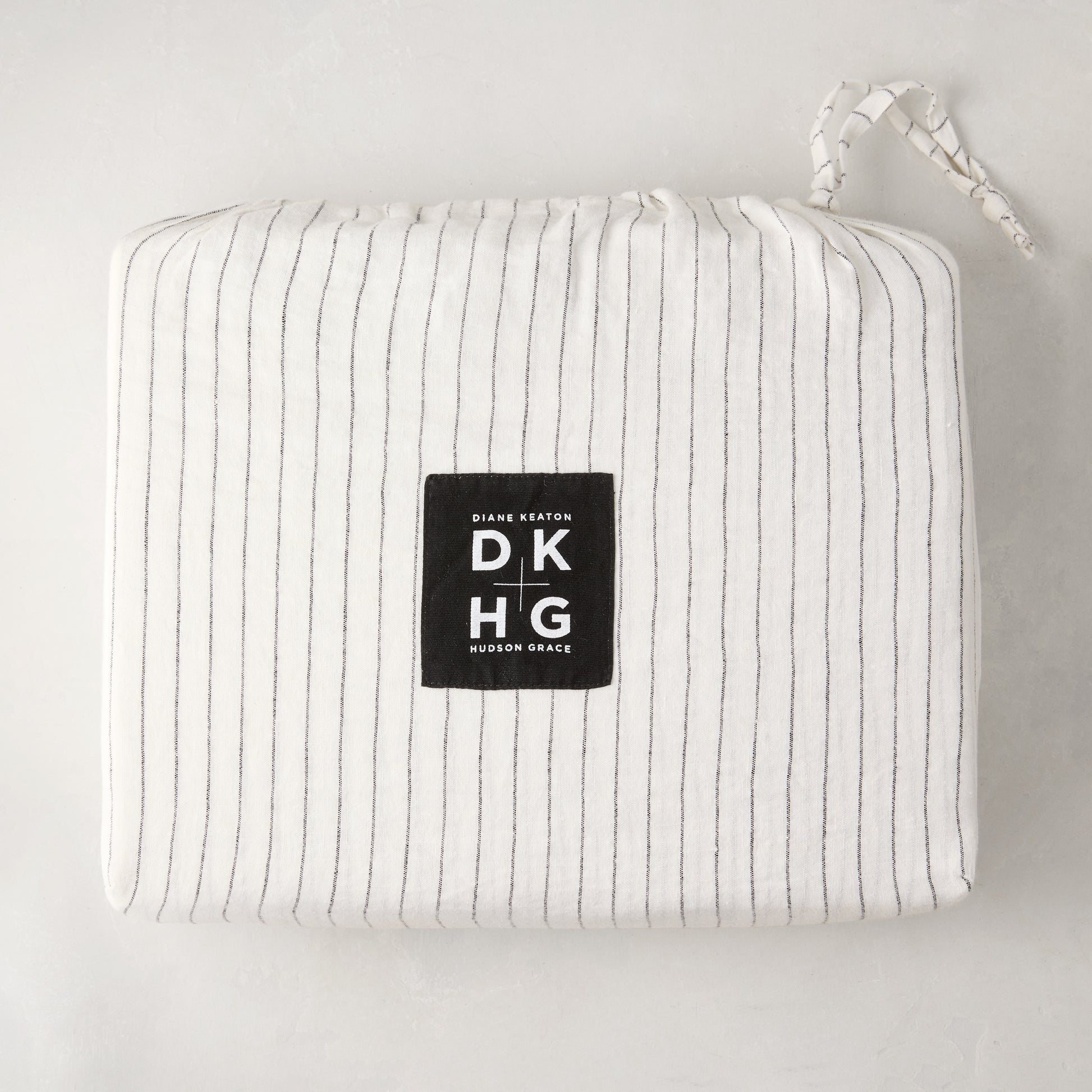 Diane Keaton + Hudson Grace Shirting Stripe Linen Duvet Cover, folded in its striped linen bag with logo.
