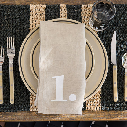 Diane Keaton + Hudson Grace Sketch Stoneware Dinner Plate with black line detail, beige napkin, and cutlery.