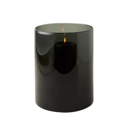 Small smoke grey hand-blown glass hurricane with a lit black pillar candle inside.