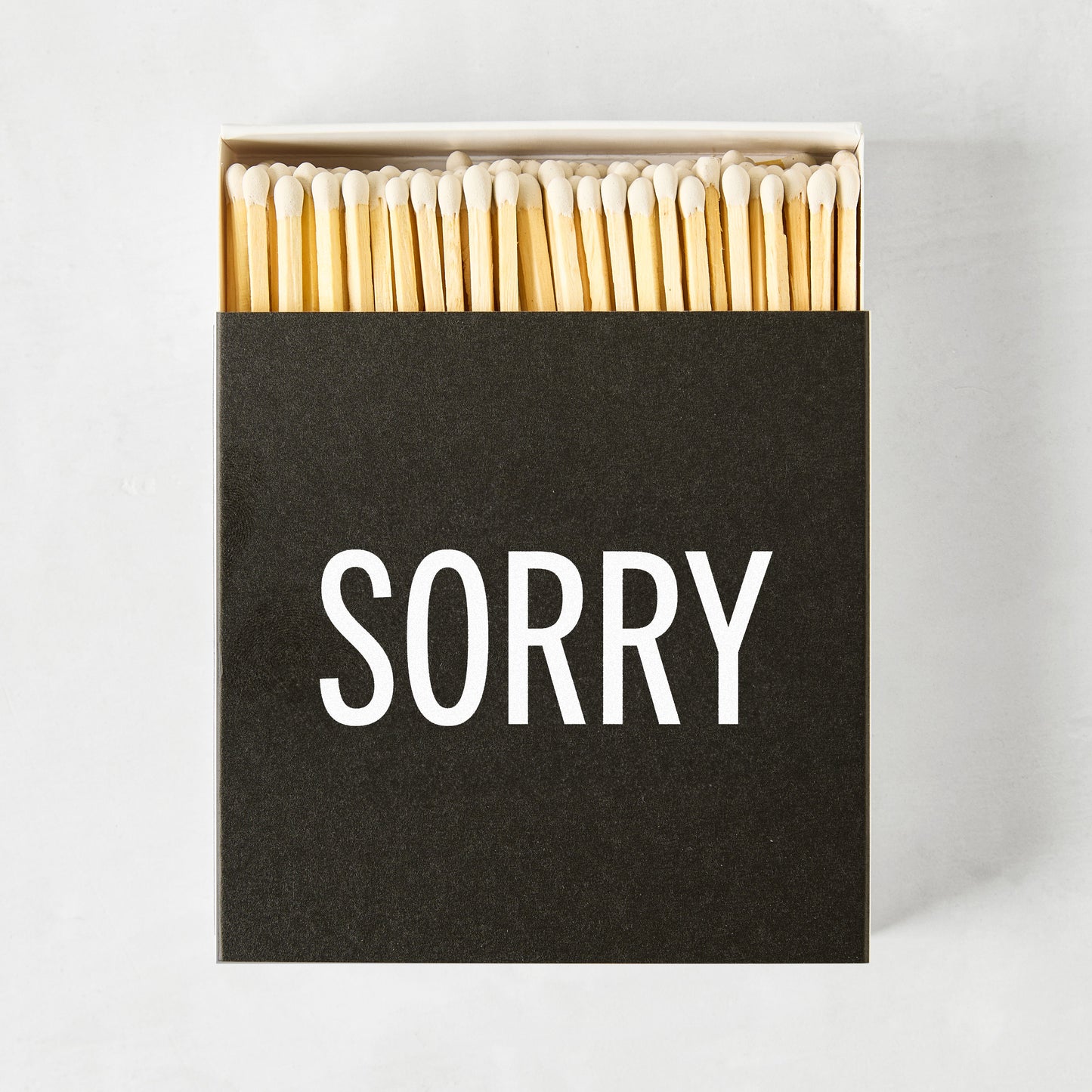 Black box of Diane Keaton + Hudson Grace "SORRY" matches with natural wood sticks.