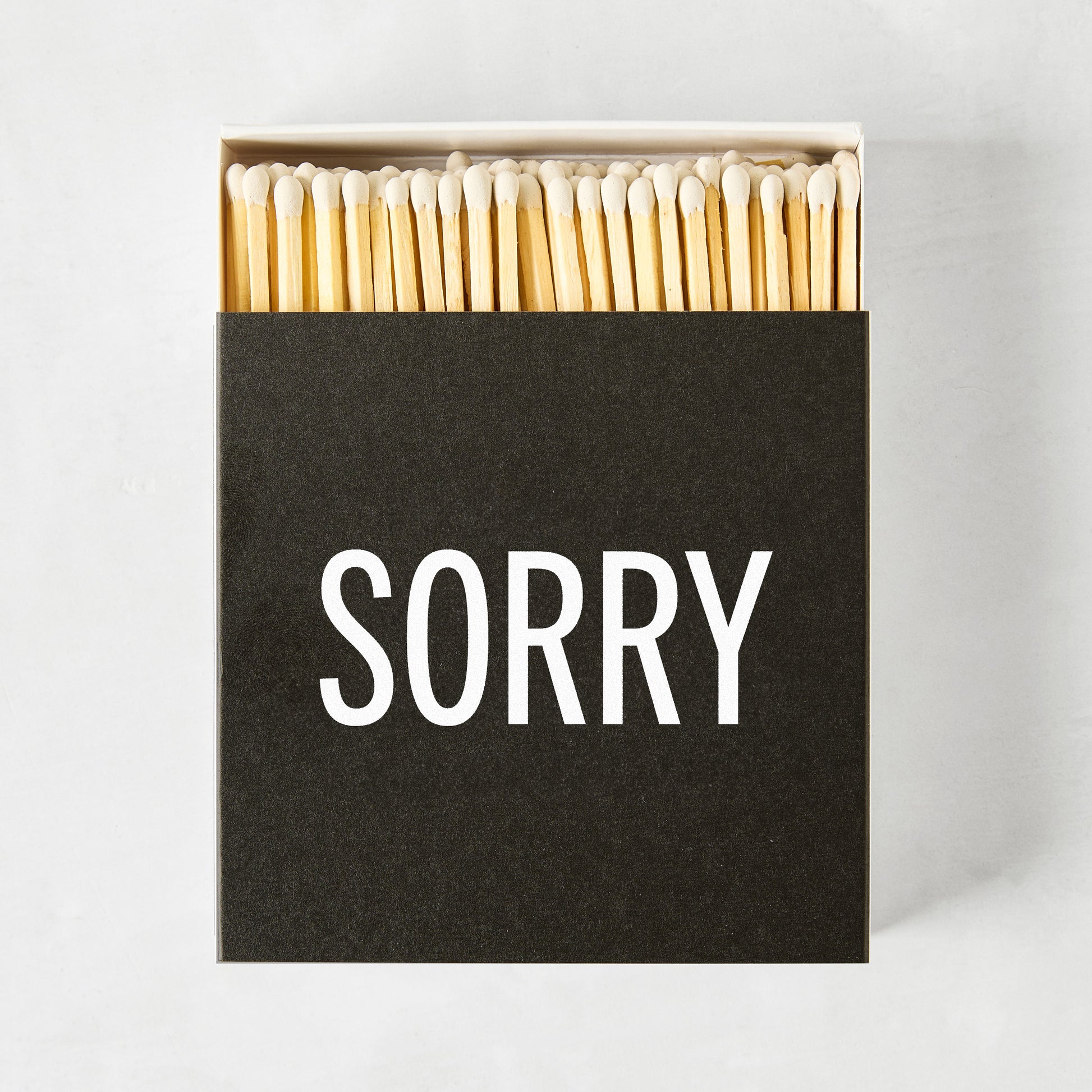 Black box of Diane Keaton + Hudson Grace "SORRY" matches with natural wood sticks.