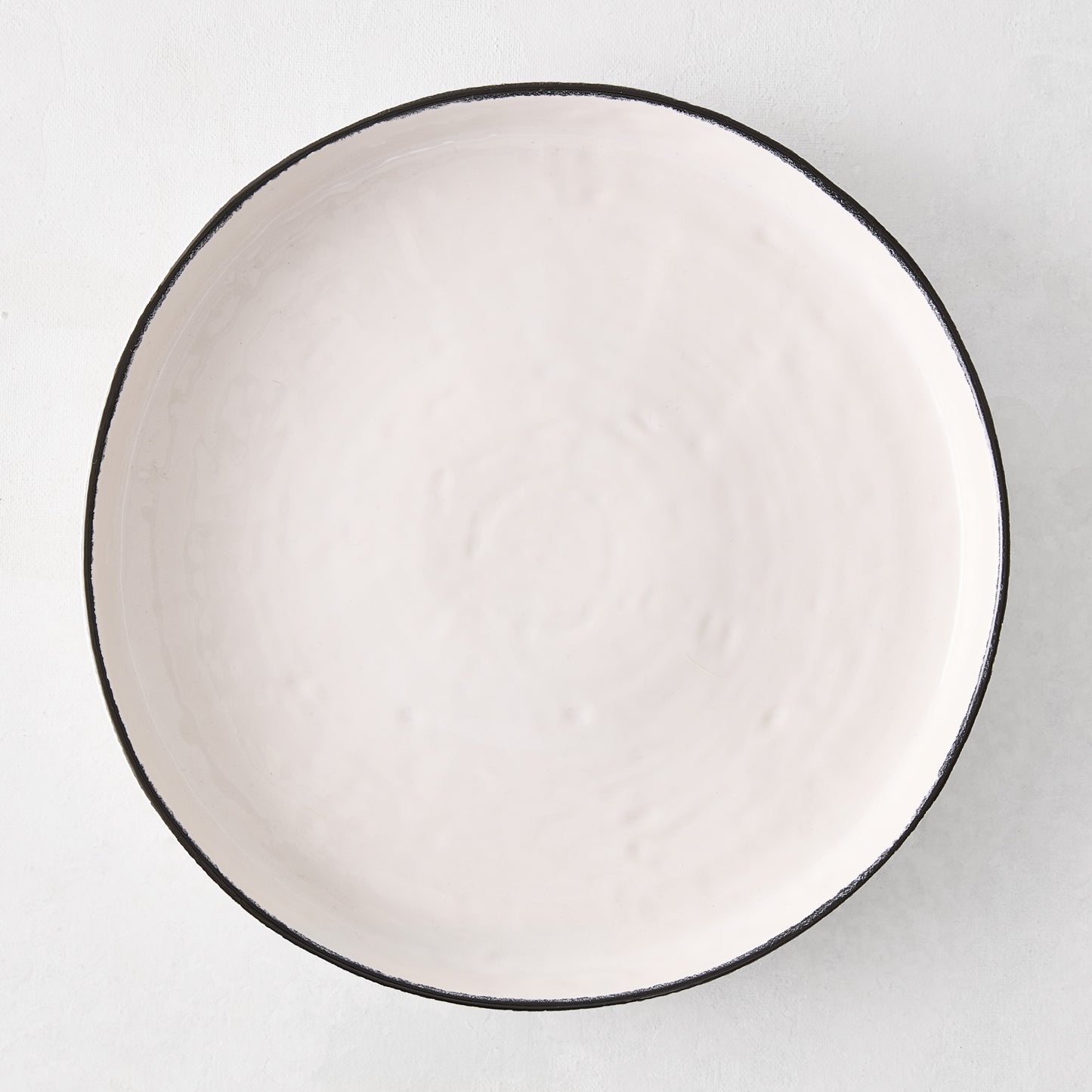 Diane Keaton + Hudson Grace Studio black rim stoneware dinner plate, irregular shape, textured white base.