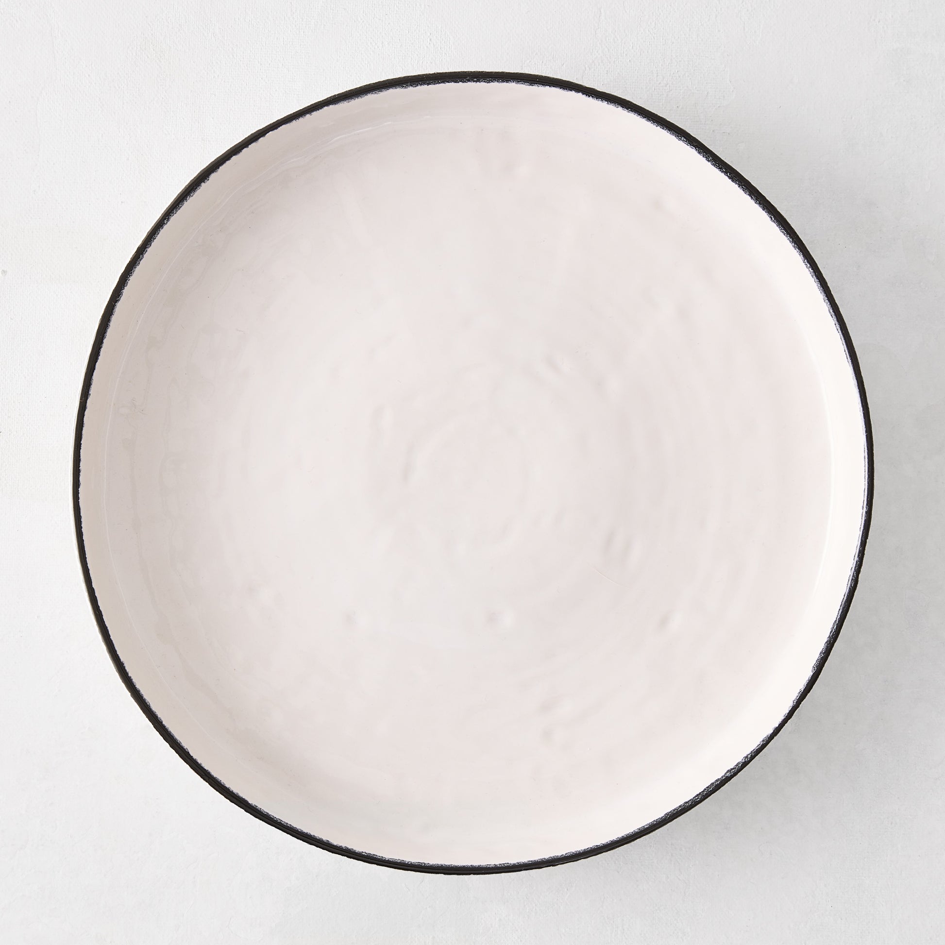 Diane Keaton + Hudson Grace Studio black rim stoneware dinner plate, irregular shape, textured white base.