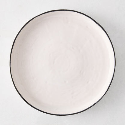 Diane Keaton + Hudson Grace Studio black rim stoneware dinner plate, irregular shape, textured white base.