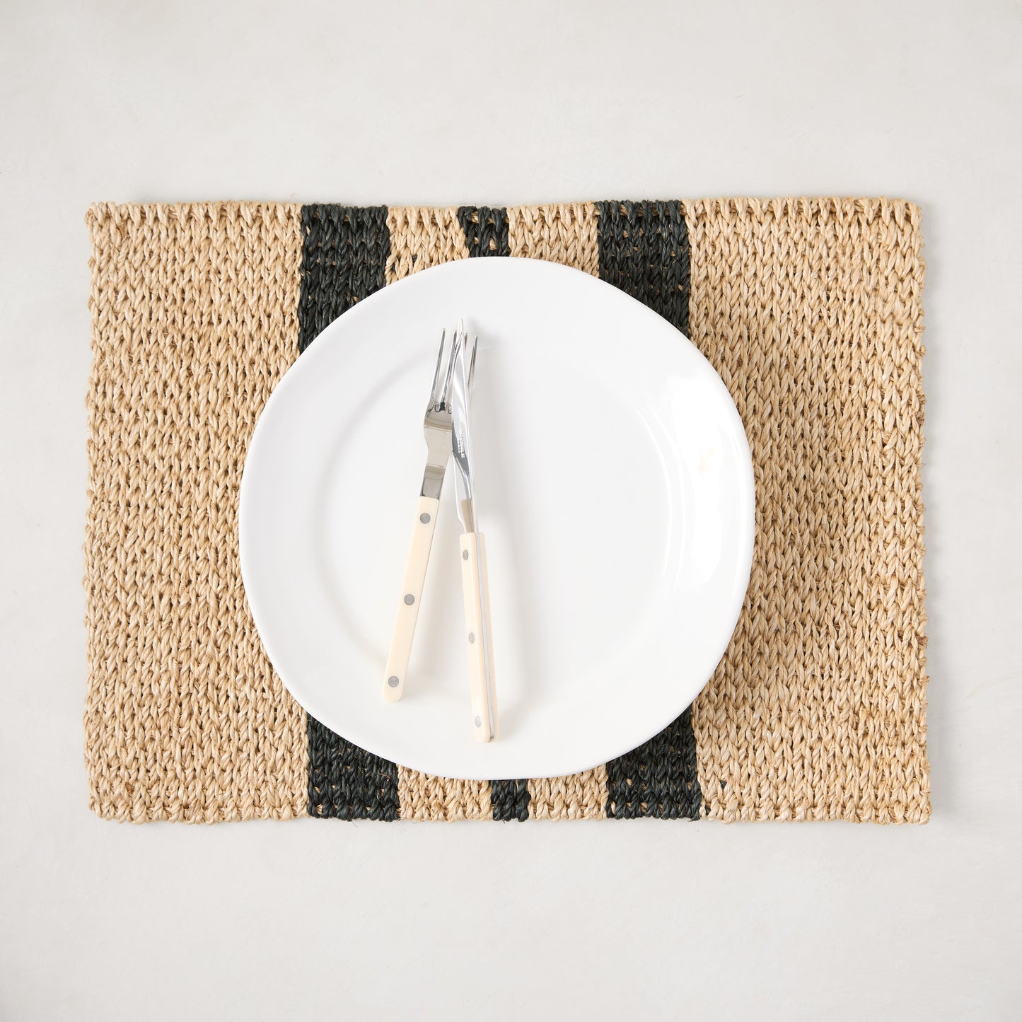 Diane Keaton + Hudson Grace tan and black stripe abaca woven placemat with white plate and forks.