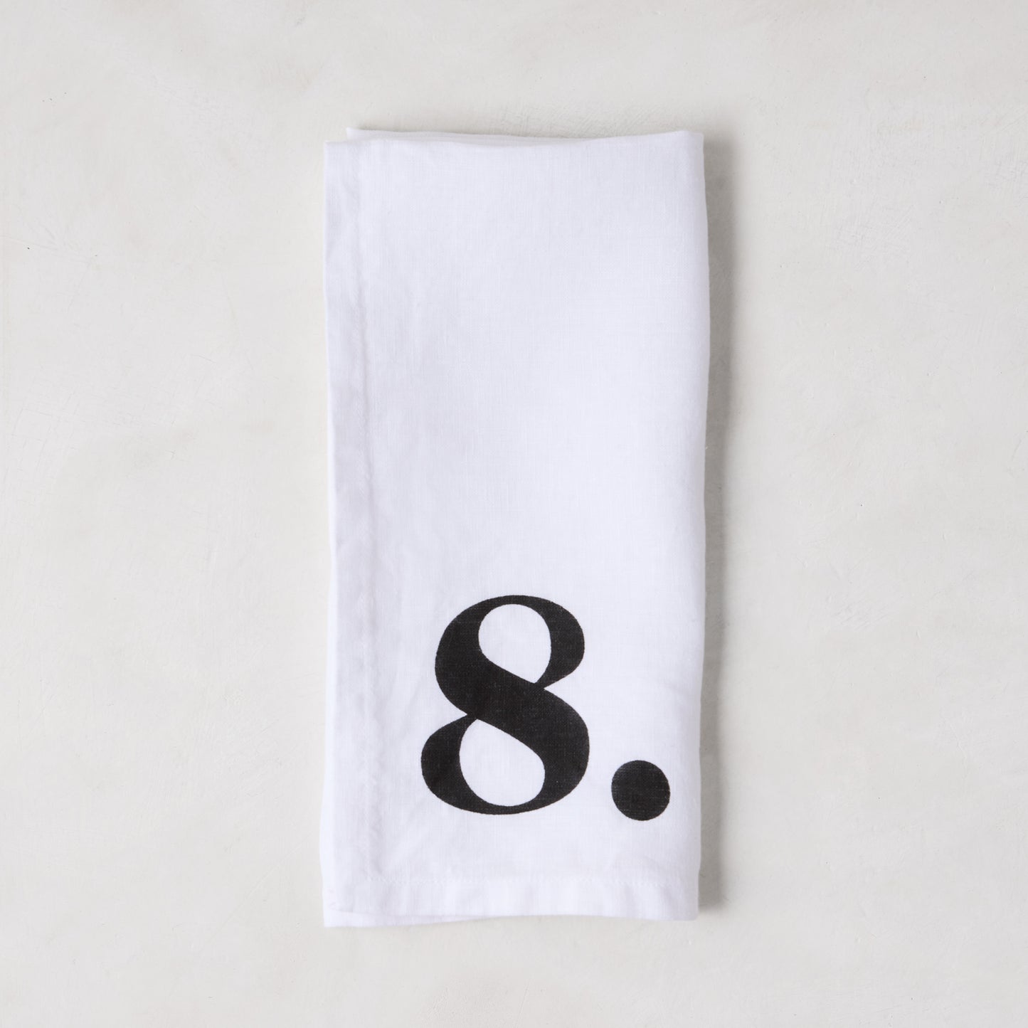 Diane Keaton + Hudson Grace white linen napkin with a bold black number 8.