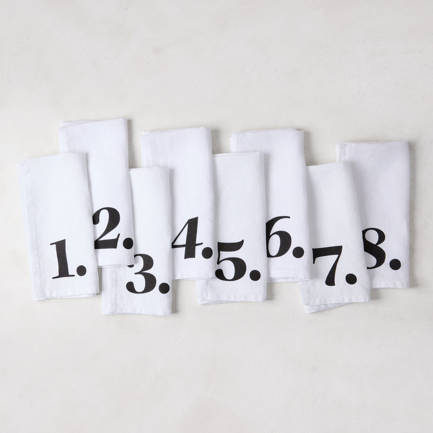 Set of 8 white linen numeric napkins with bold black numbers 1-8 from the Diane Keaton + Hudson Grace collection.