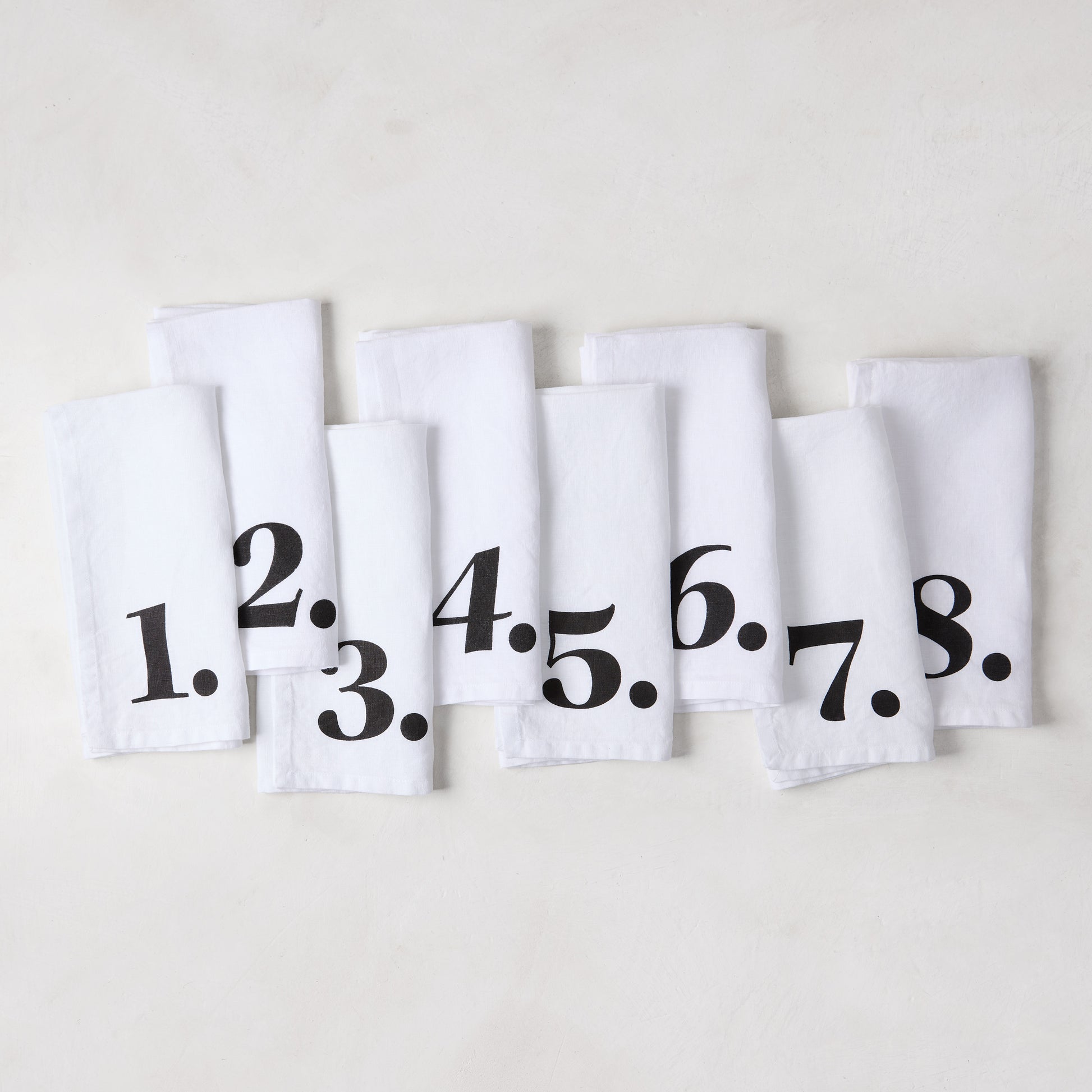 Set of 8 white linen numeric napkins with bold black numbers 1-8 from the Diane Keaton + Hudson Grace collection.