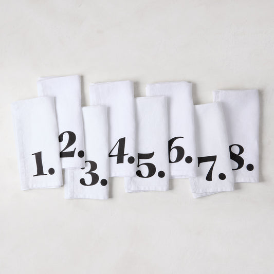 Set of 8 white linen numeric napkins with bold black numbers 1-8 from the Diane Keaton + Hudson Grace collection.