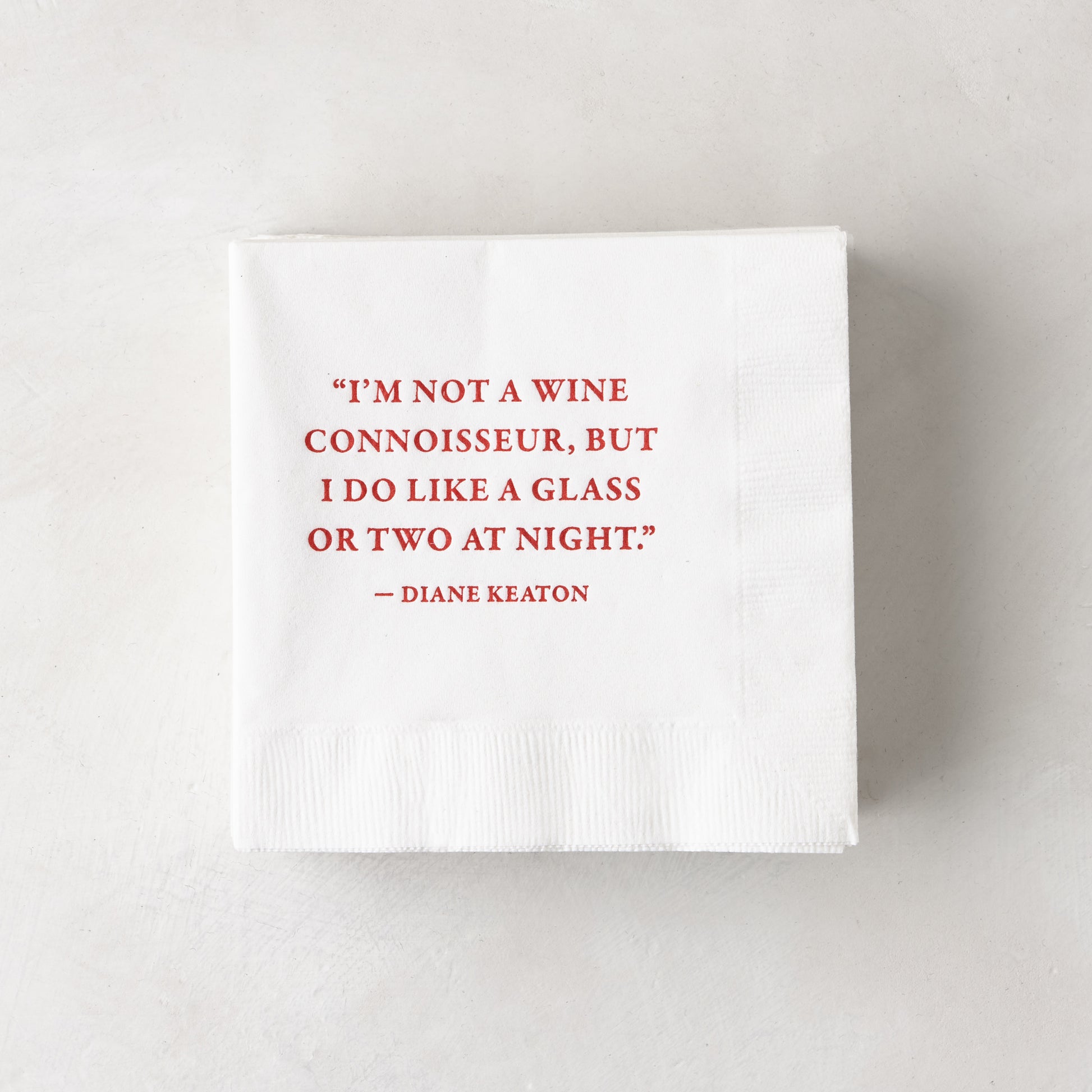 White 5.5" square 3-ply paper cocktail napkins with a red Diane Keaton quote.