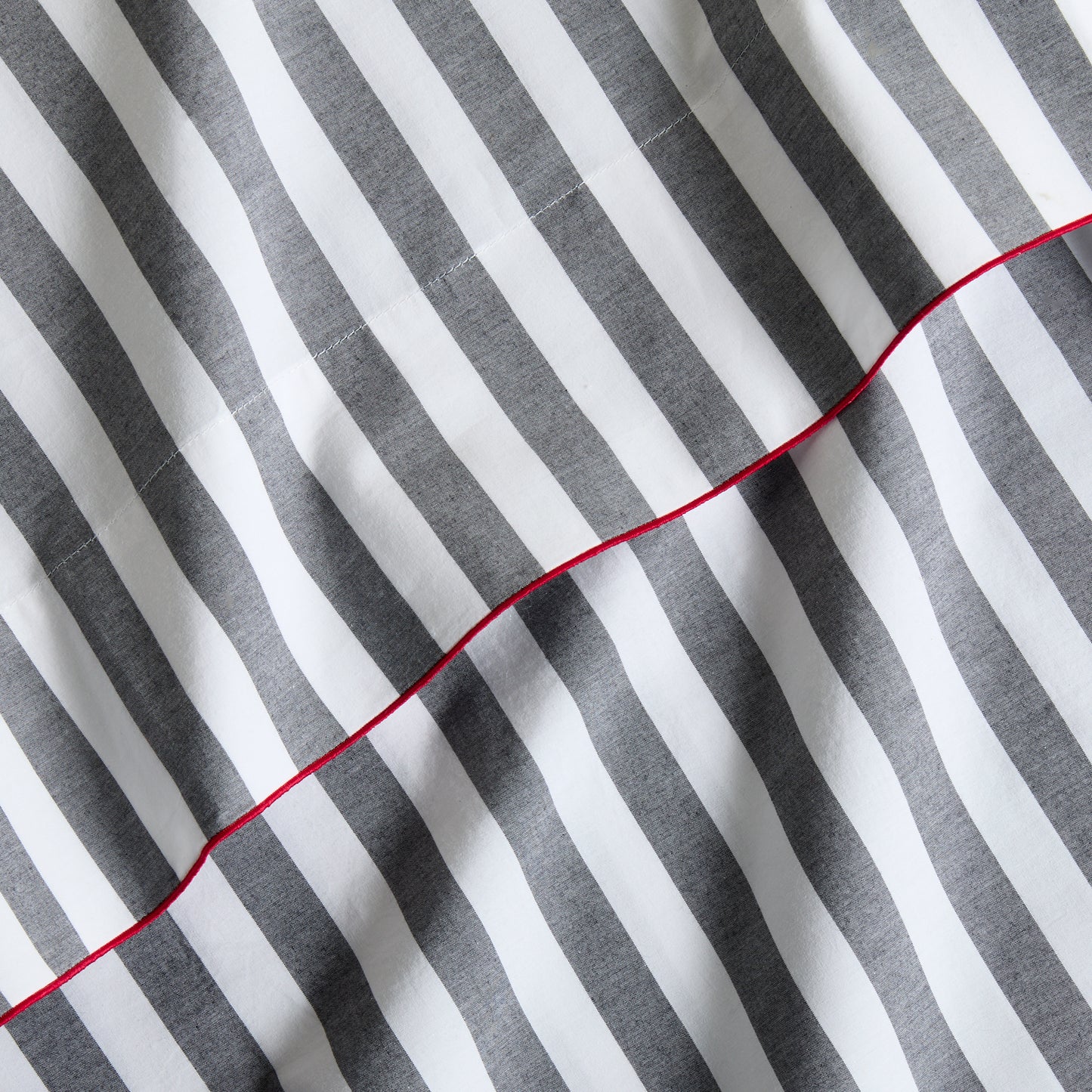 Diane Keaton + Hudson Grace gray and white striped percale sheet set with red trim.