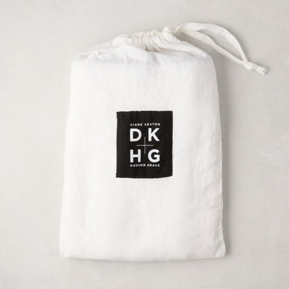 White washed linen drawstring bag with a black "Diane Keaton DKHG Hudson Grace" label.