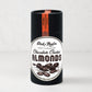Dick Taylor Chocolate Coated Almonds in a tall, black cylindrical container with a white and black label.