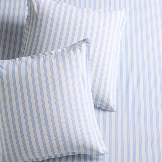 Two Dobby Blue Stripe Cotton Euro Shams with subtle texture, on a matching striped sheet.