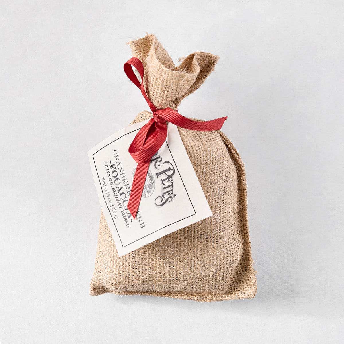 Dr. Pete's Cranberry Herb Focaccia bread mix in a tan burlap sack tied with a red ribbon and a white product label.