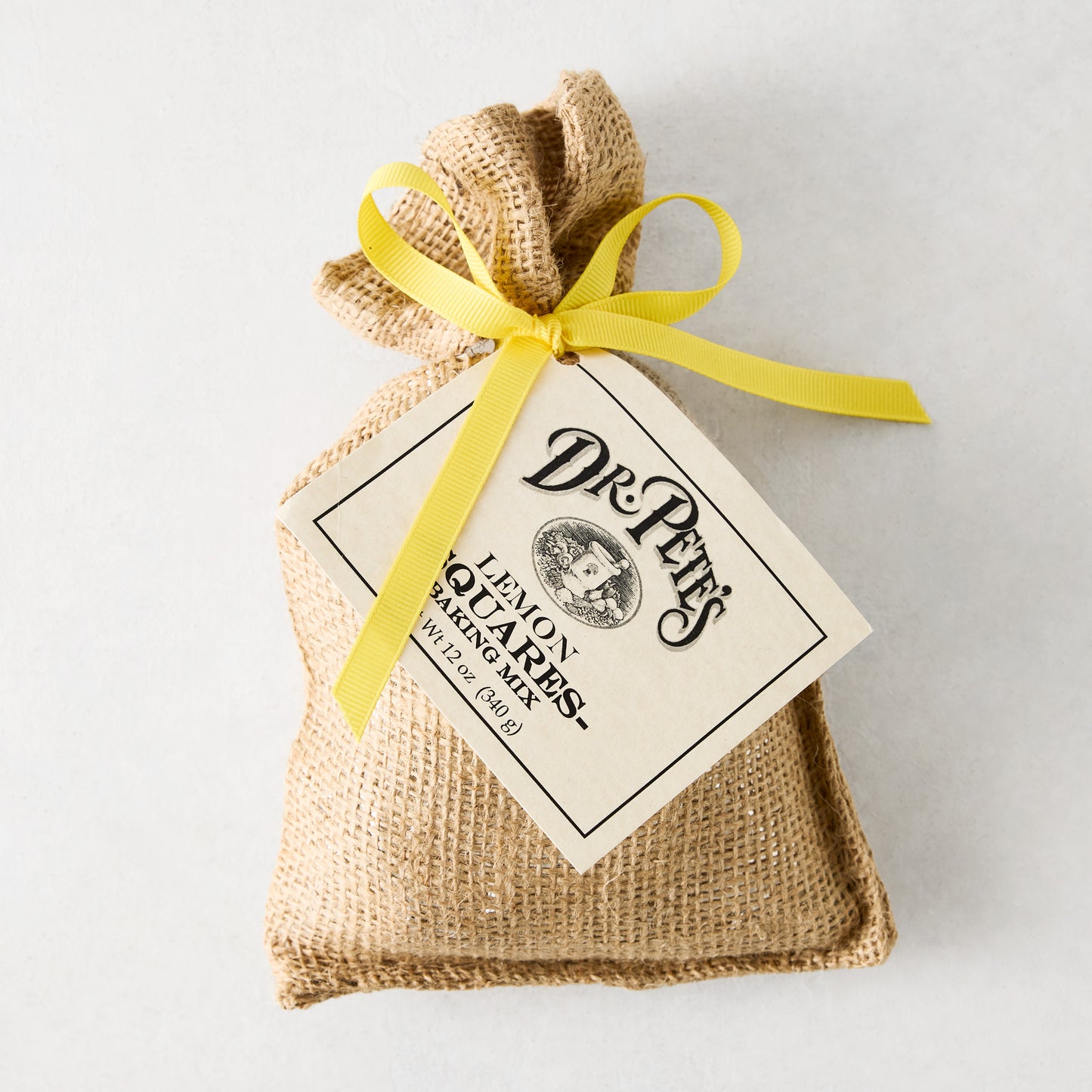 Dr. Pete's Lemon Squares baking mix in a burlap sack with a yellow ribbon and branded tag.