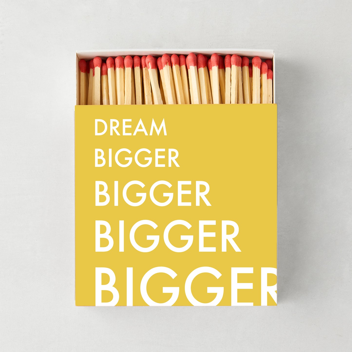 Oversized "Dream Bigger" matches in a yellow box with white text, showing red-tipped wooden matchsticks.