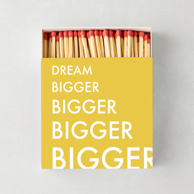 Oversized "Dream Bigger" matches in a yellow box with white text, showing red-tipped wooden matchsticks.