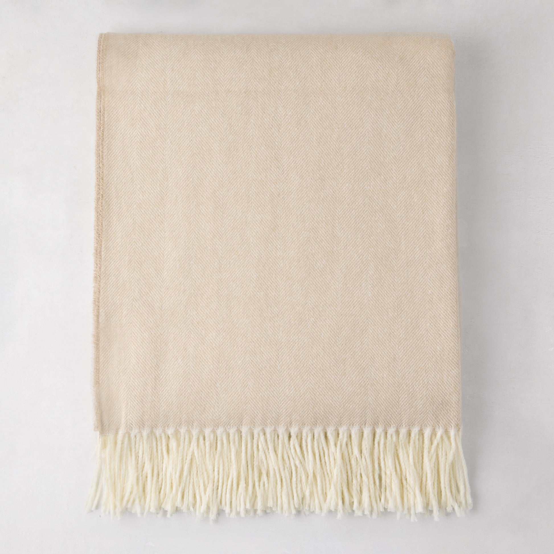 Dune Italian Herringbone Throw Blanket, cashmere-soft cotton-acrylic, with decorative fringe.
