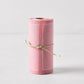 Dusty pink tear-off cotton cocktail napkin roll with white stitching, tied with twine.