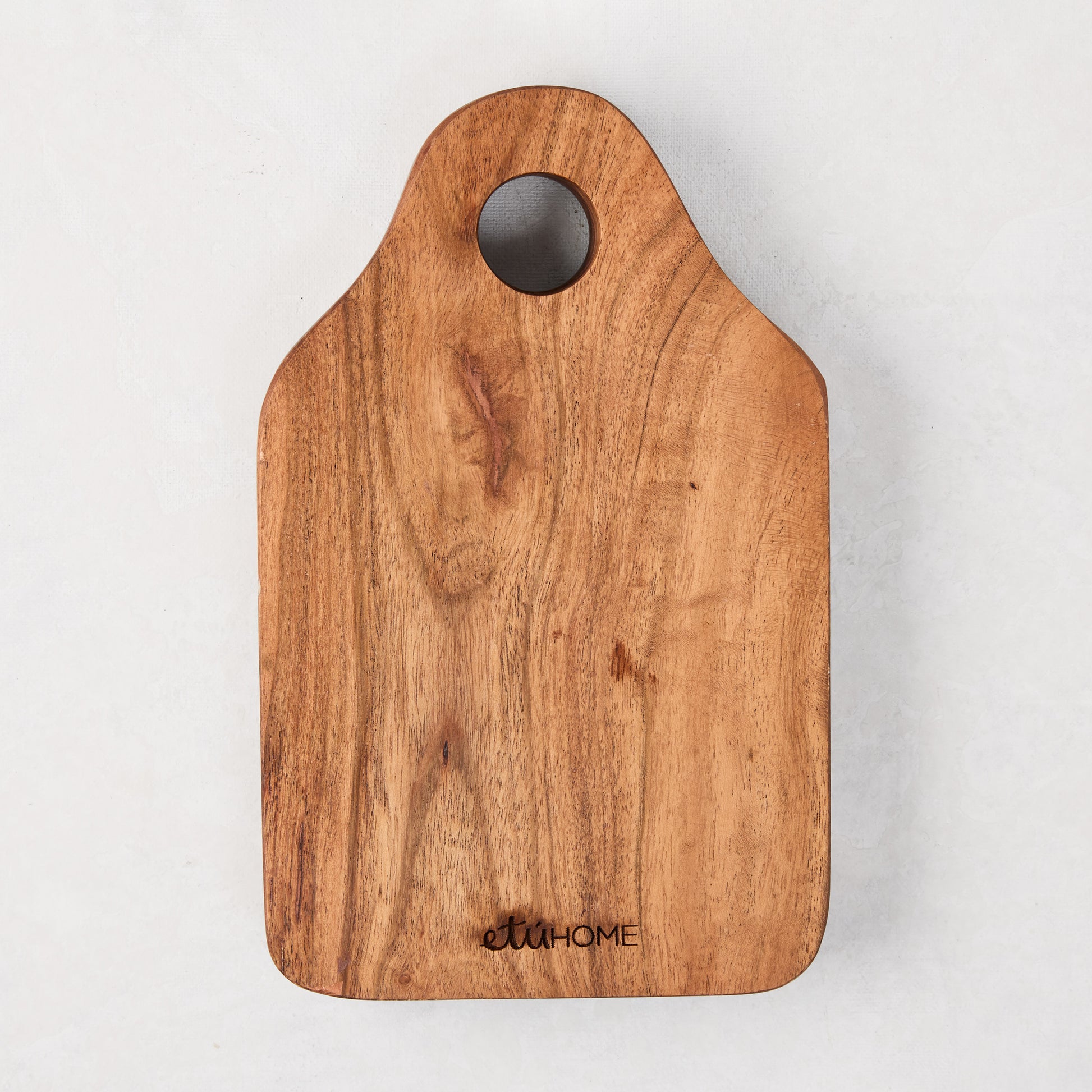 Acacia wood cheese board with natural grain, rounded edges, and a top hanging hole.