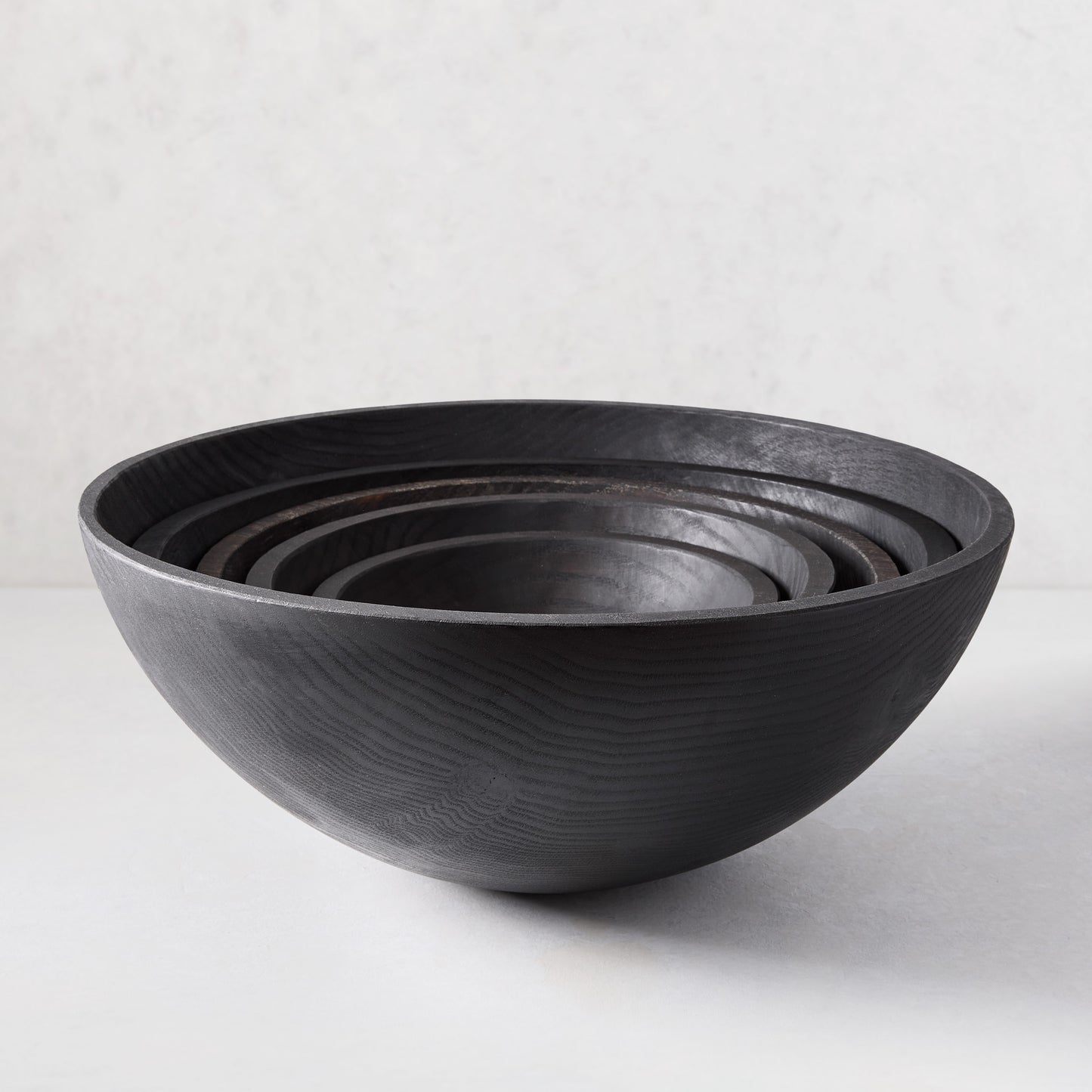 Ebonized wood bowl, 13", dark finish highlighting wood grain, nested with smaller bowls.