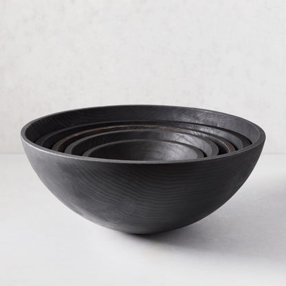 Ebonized wood bowl, 21", with visible grain, nested with smaller dark wood bowls.