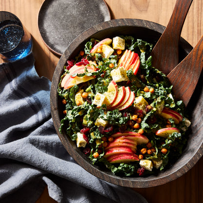 Ebonized 21" spalted wood bowl filled with kale salad, apples, and cranberries, with wood servers.