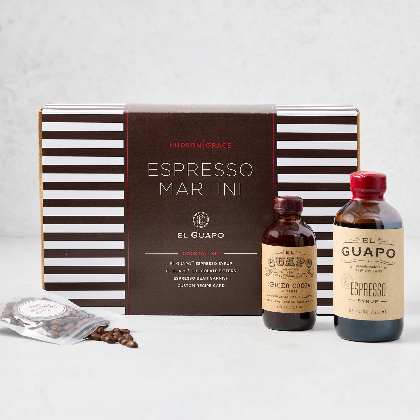 El Guapo Espresso Martini Cocktail Kit with striped box, espresso syrup, spiced cocoa, and coffee beans.