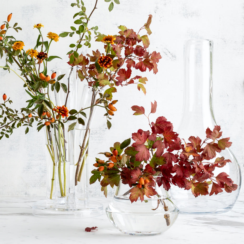Elise Glass Vase: Clear, mouth-blown glass vase with a traditional shape, filled with autumn foliage and berries.