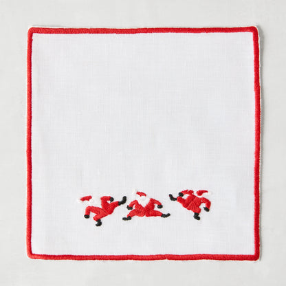 White linen coaster with red embroidered Santa figures and a red border.