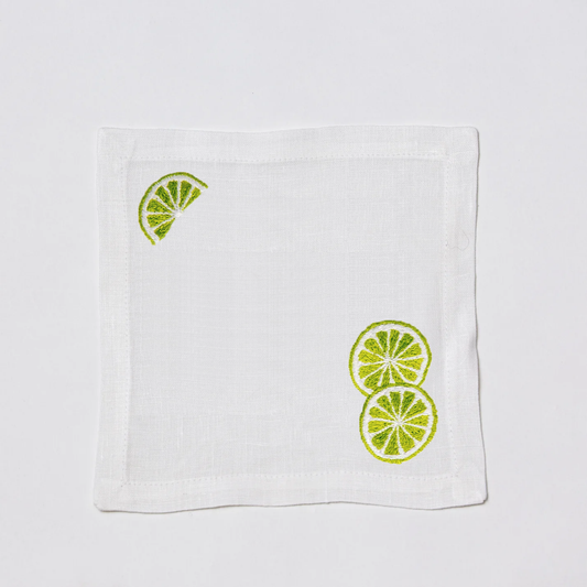 White linen cocktail napkin coaster with embroidered lime slices.