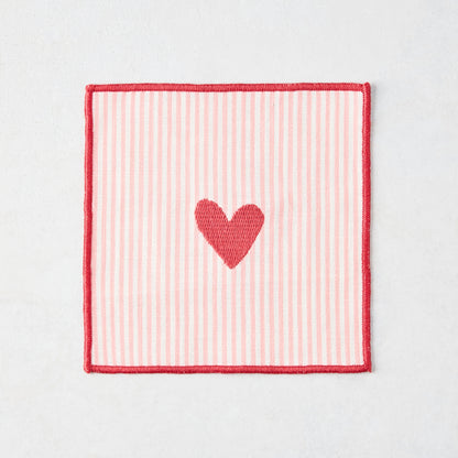 Cotton coaster with pale pink and white stripes, red embroidered heart, and red edge.