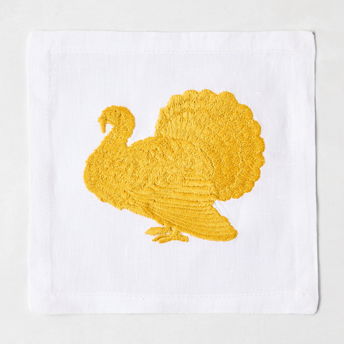 5.5-inch white linen cocktail napkin with a gold embroidered turkey design.