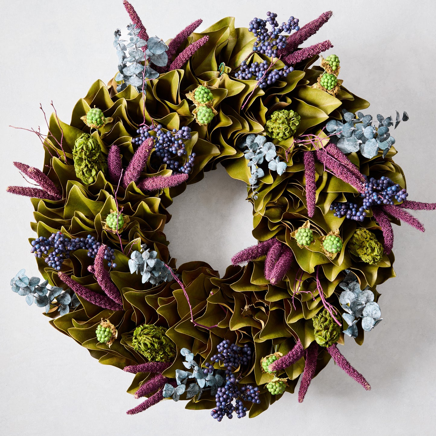 Enchanted Forest Wreath with green magnolia leaves, blue juniper berries, plum millet, and green magnolia pods.
