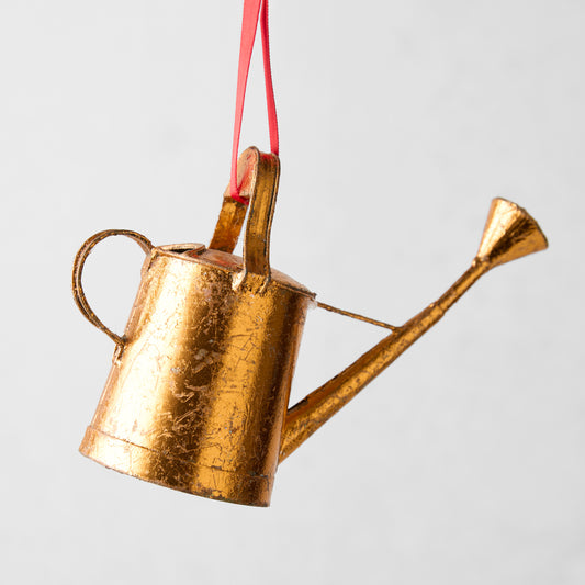 Gold metal watering can Christmas tree ornament with red ribbon.
