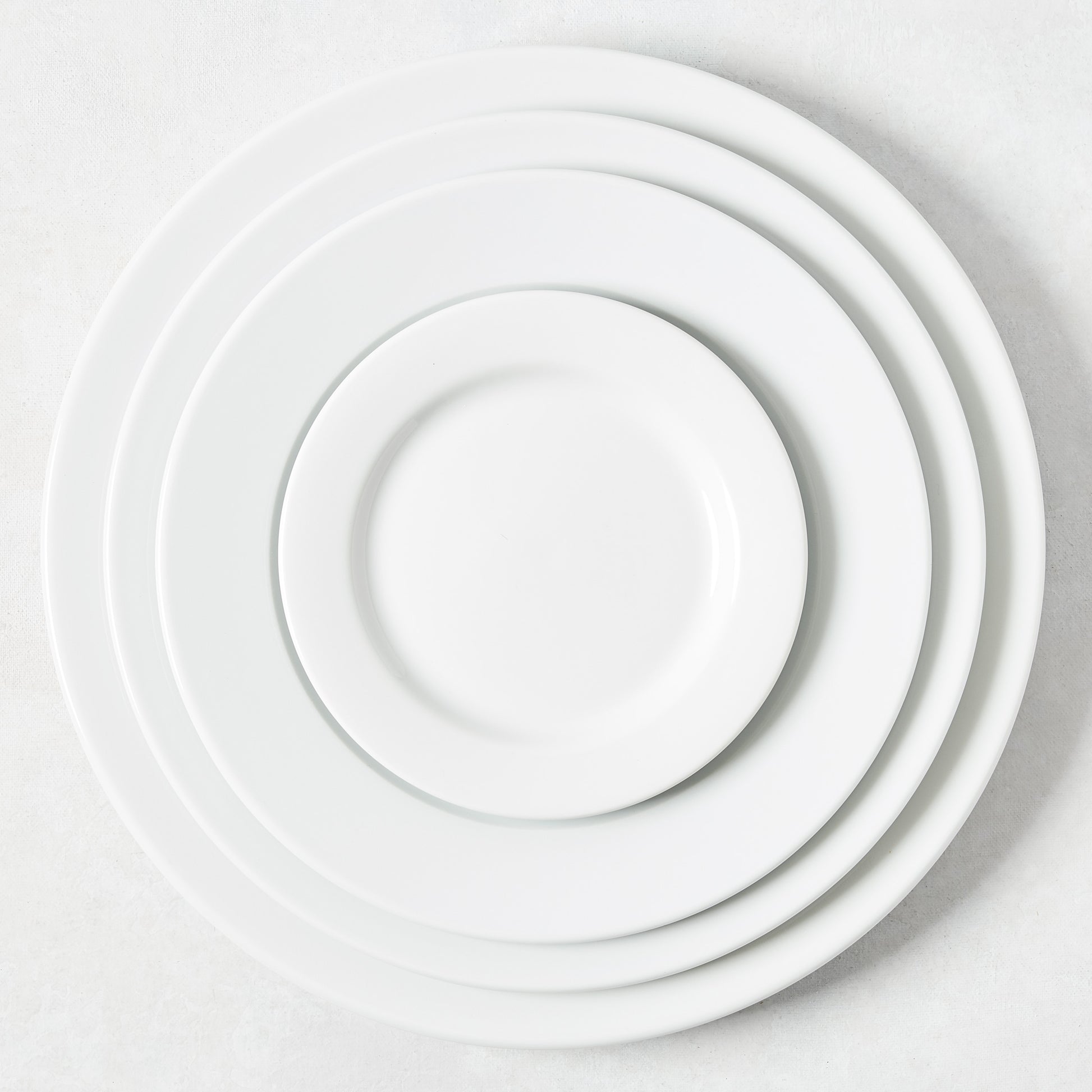 Hudson Grace Everyday Porcelain Buffet Plate, 12.2" Dia, white, classic rim, stacked with smaller plates.
