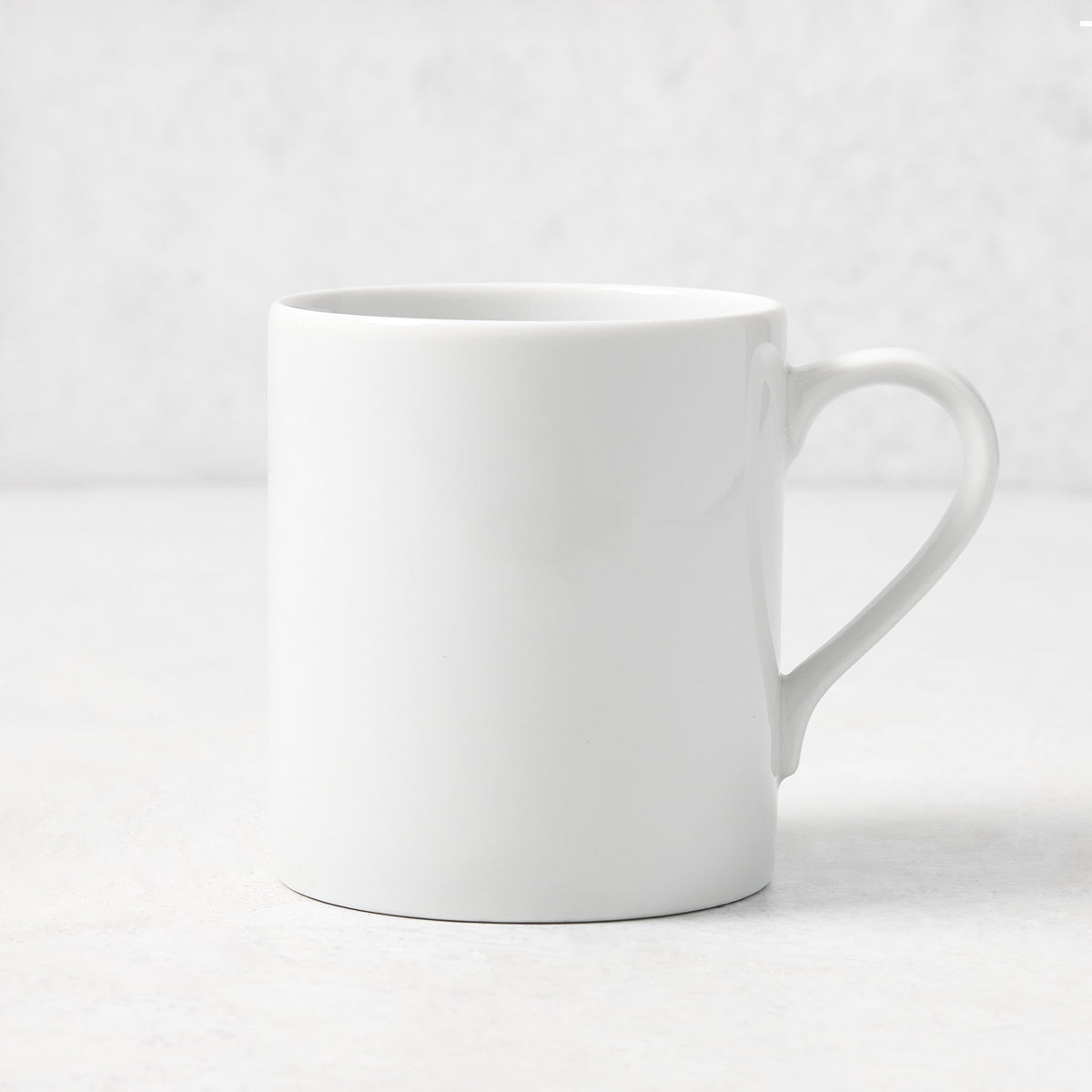 White porcelain mug with a curved handle from the Hudson Grace Everyday collection, 4.3 inches tall.