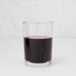 Clear, simple Hudson Grace Everyday Wine Glass filled with red liquid on a white background.