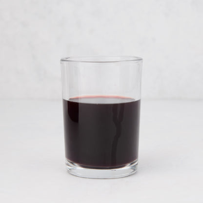 Clear, simple Hudson Grace Everyday Wine Glass filled with red liquid on a white background.