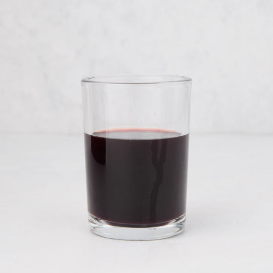 Clear, simple Hudson Grace Everyday Wine Glass filled with red liquid on a white background.