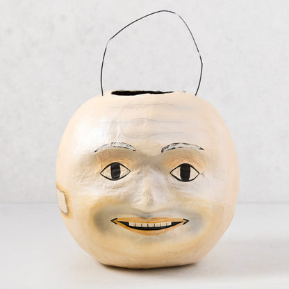 Vintage-style papier-mâché Halloween candy bucket, 10"H, with a distressed cream moon face and black wire handle.