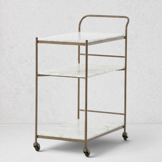 Felix antique brass bar cart with three white marble rectangular shelves on casters.