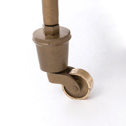 Close-up of an antique brass caster wheel on a Felix bar cart.