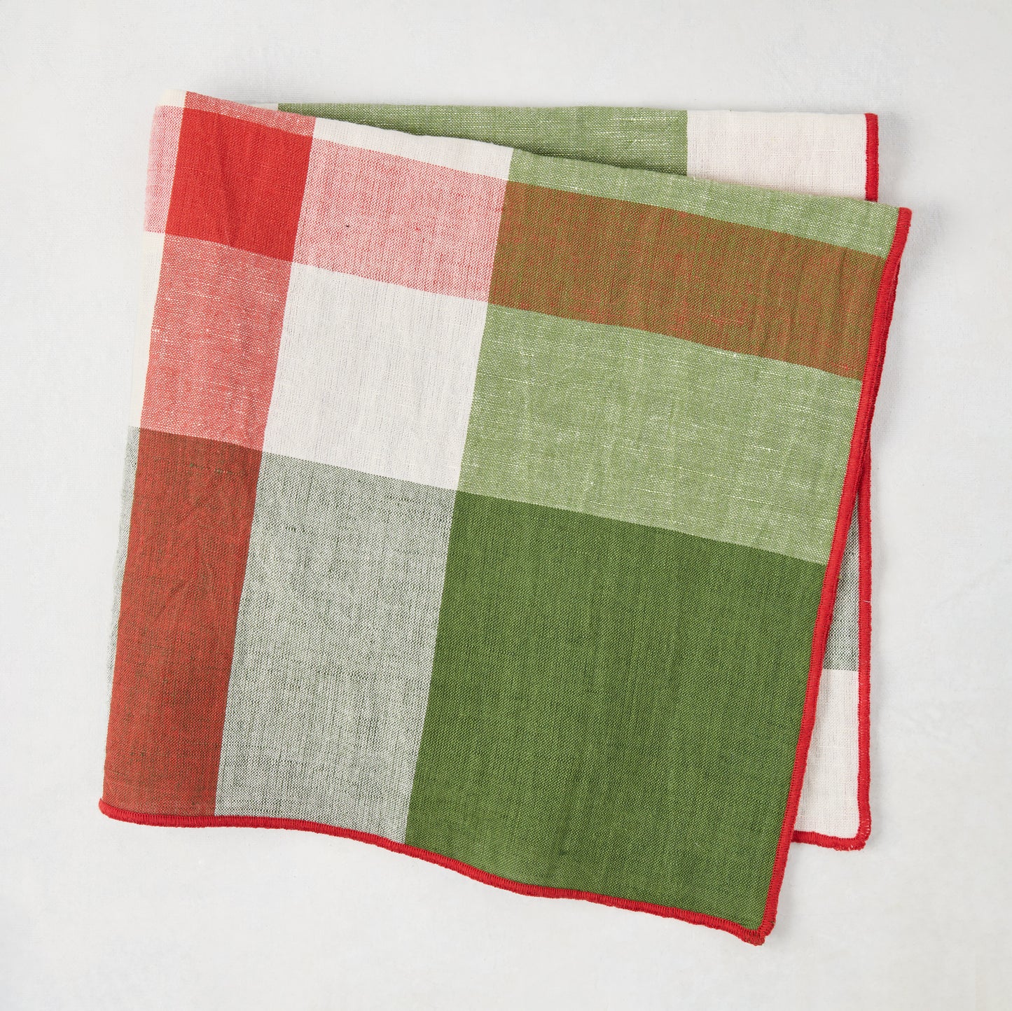 Festive green and red plaid cotton napkin with embroidered red trim, 22" square.