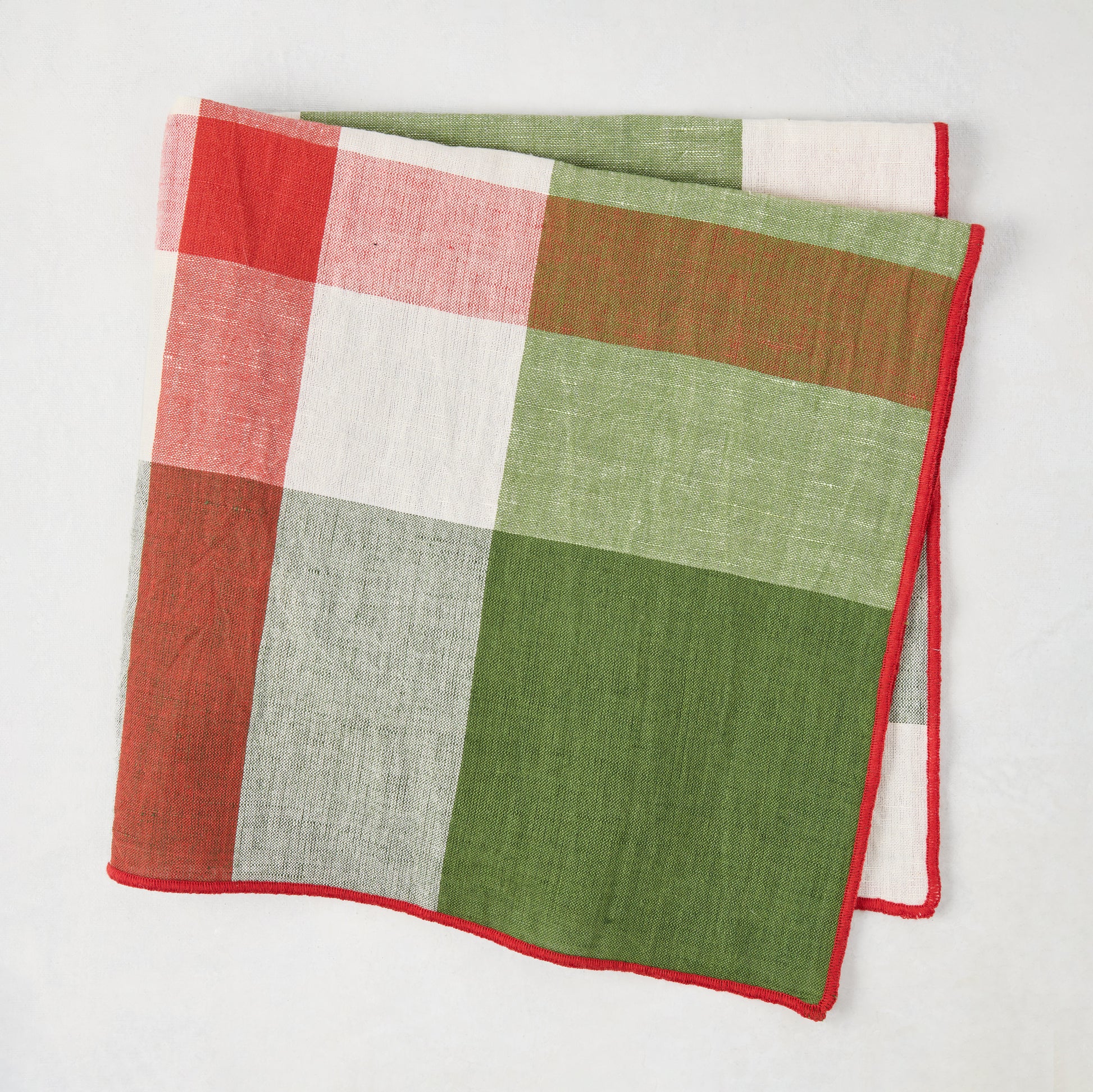 Festive green and red plaid cotton napkin with embroidered red trim, 22" square.