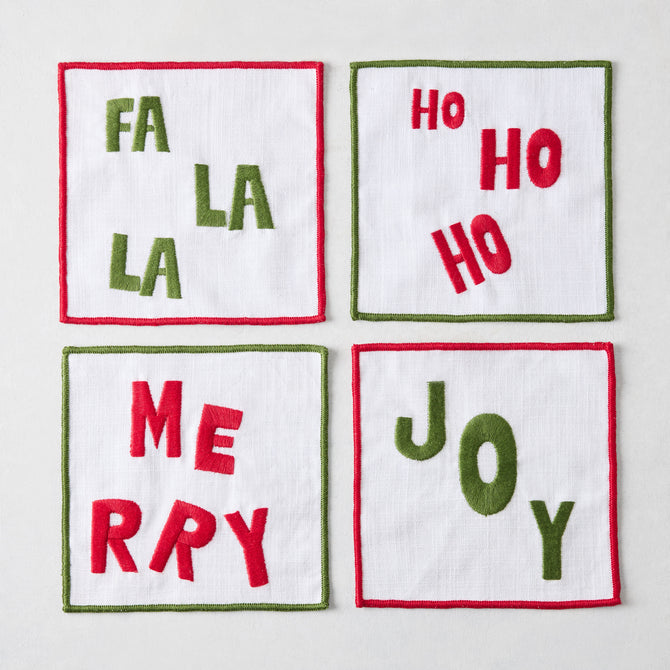 Set of four square white fabric coasters with red and green festive embroidered holiday text and stitched borders.
