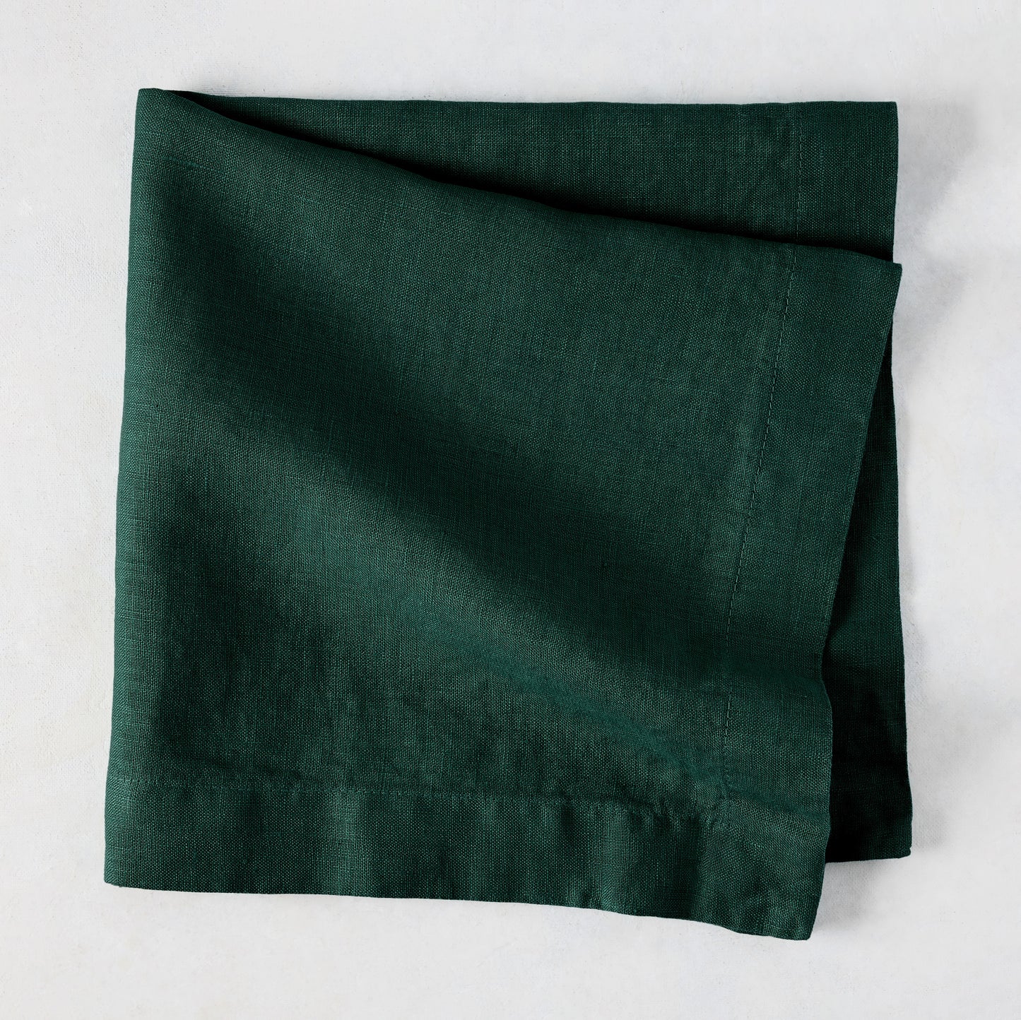 Fir HG Hand-dyed Linen Napkin, dark forest green, folded square, 22-inch, mitered corners.