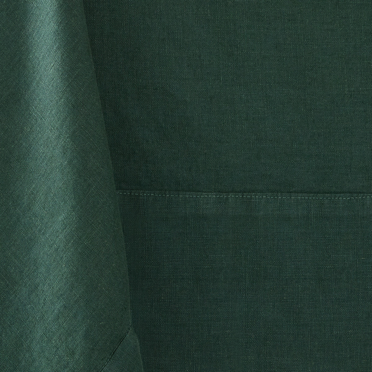 Fir green hand-dyed 100% linen tablecloth with visible fabric texture and a stitched mitered border detail.