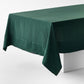 Hand-dyed fir green linen tablecloth with mitered corner detailing draped over a white table.